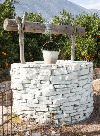 Pozo de piedra con cubo junto a un campo de naranjos en la huerta de Valencia